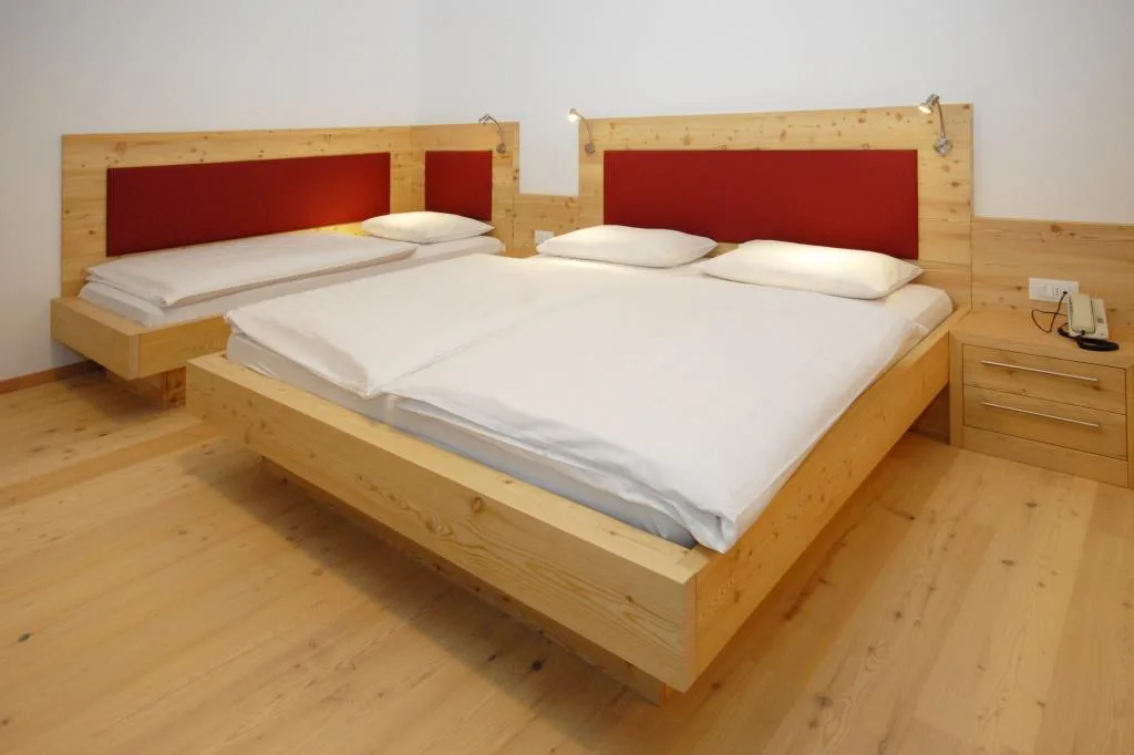 Dettaglio di letto matrimoniale in legno con testiera rossa