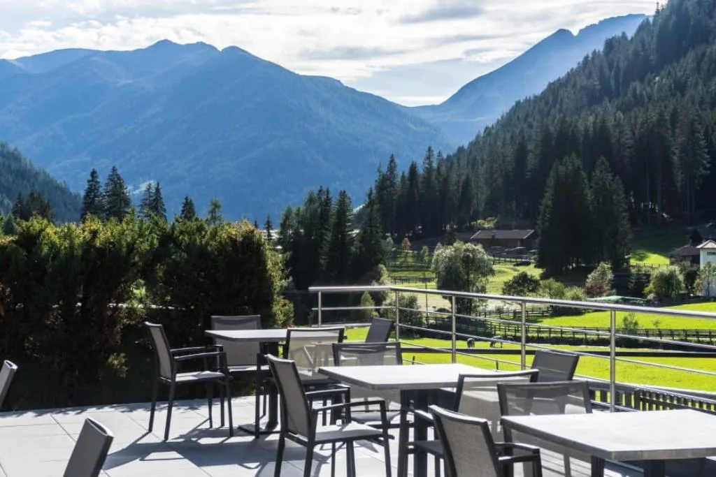 Terrazza con tavoli e sedie e vista panoramica su montagne e prati verdi