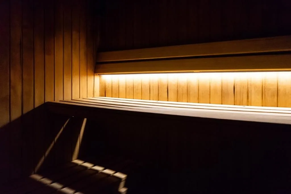 Interno della sauna con panche in legno e illuminazione calda soffusa