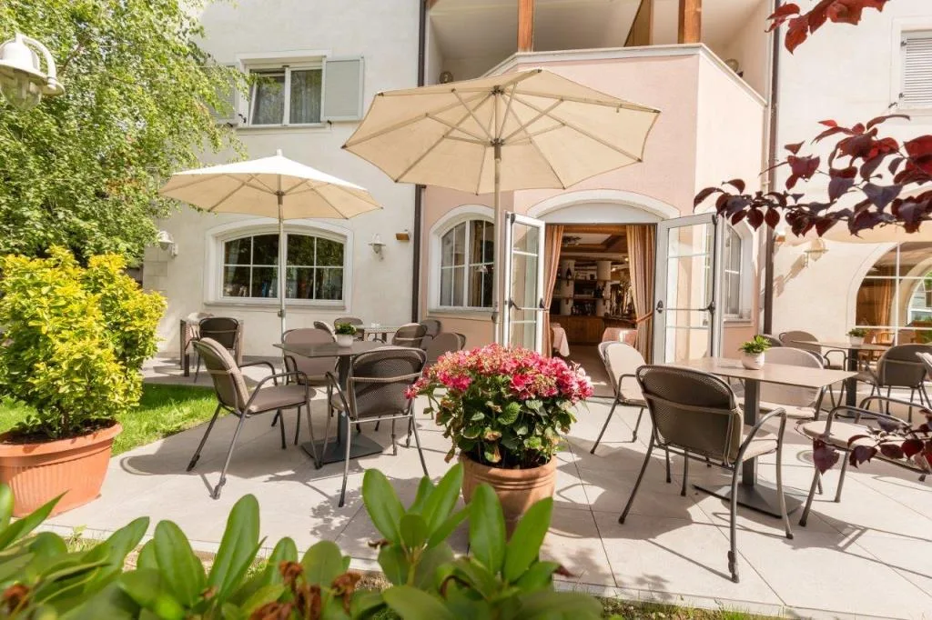 Terrazza esterna dell'hotel con tavoli, sedie e ombrelloni tra il verde