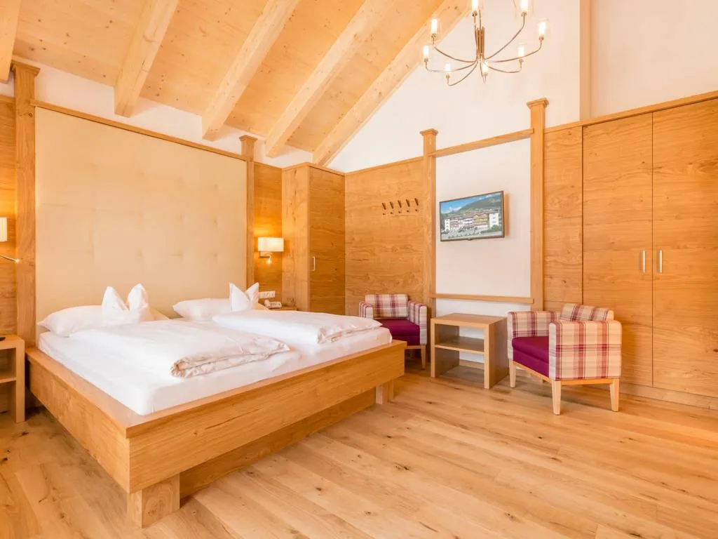 Camera da letto in legno con letto matrimoniale, poltrone e soffitto travi