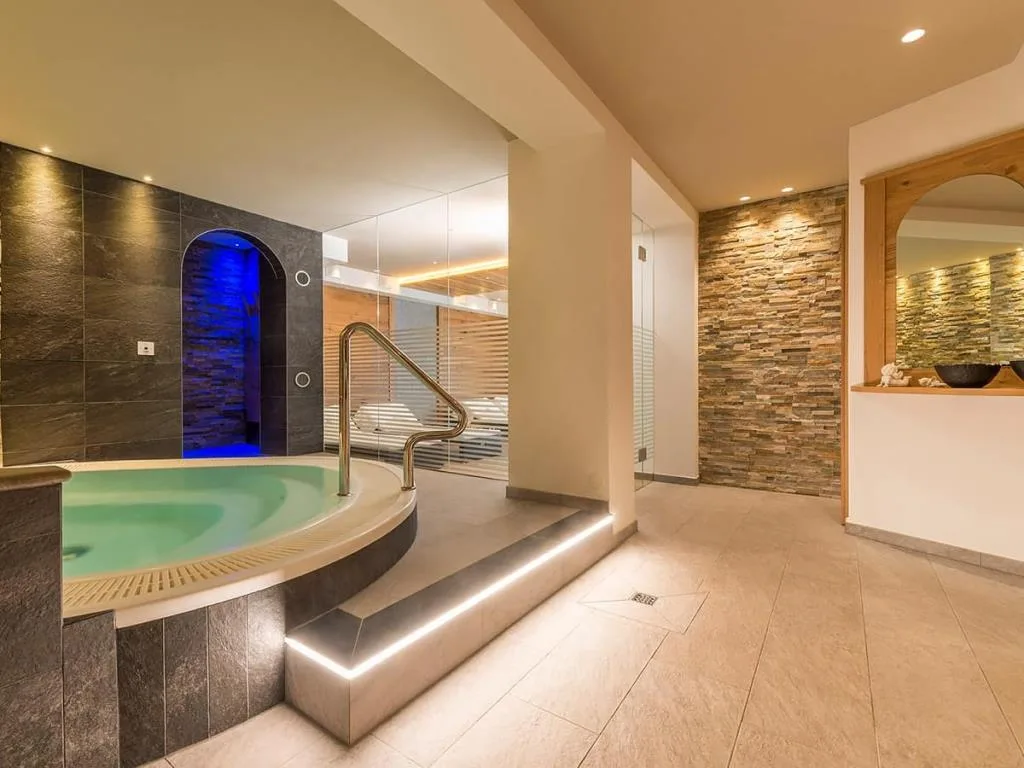 Area wellness con vasca idromassaggio, sauna e pareti in pietra
