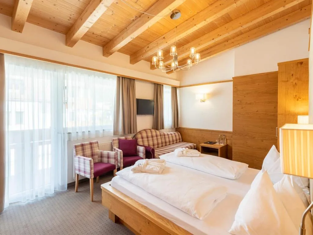 Camera spaziosa con letto, divano, poltrone e soffitto con travi in legno