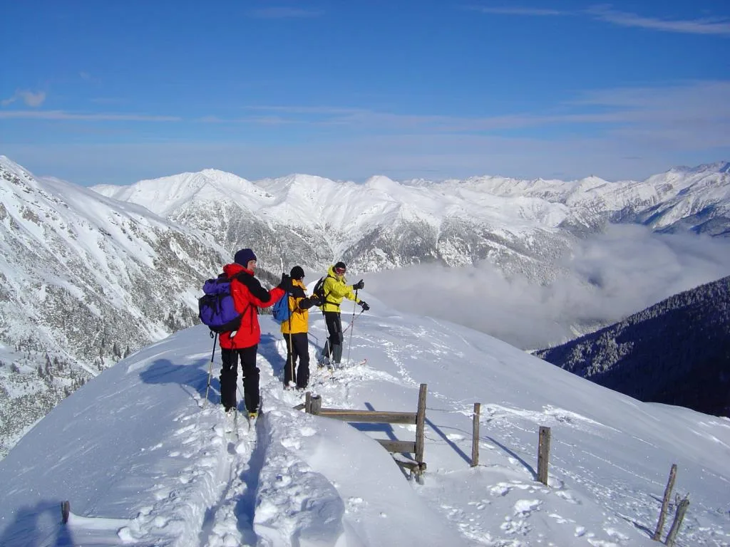 Escursionisti con sci d'alpinismo su cresta innevata con panorama alpino