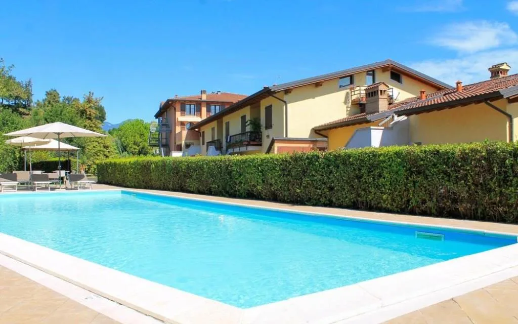 Piscina esterna rettangolare con acqua azzurra e edificio dell'hotel sullo sfondo