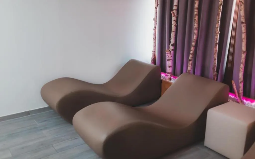 Zona relax della spa con lettini ergonomici e tende decorate con rami