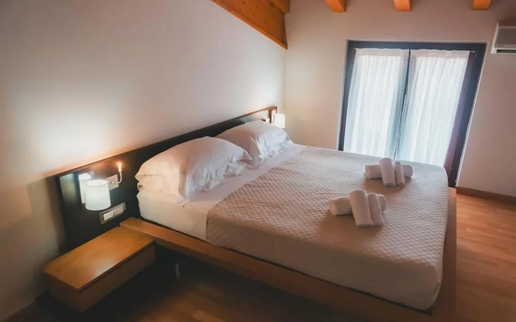 Camera da letto con letto matrimoniale, travi in legno e ampia finestra