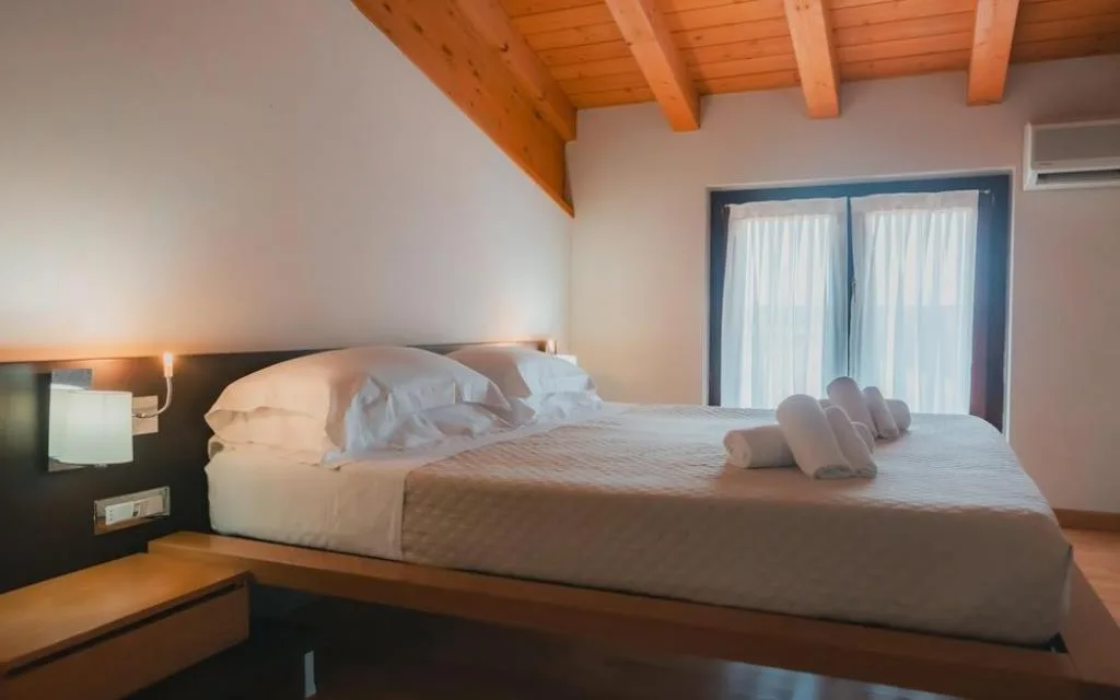 Camera matrimoniale con soffitto in legno mansardato e luce naturale