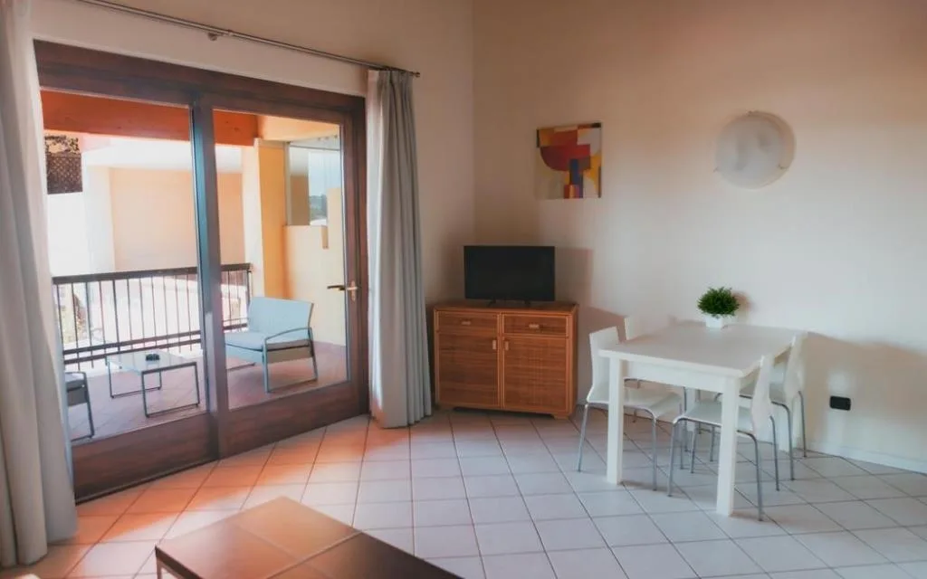Soggiorno dell'appartamento con zona pranzo, TV e accesso al balcone