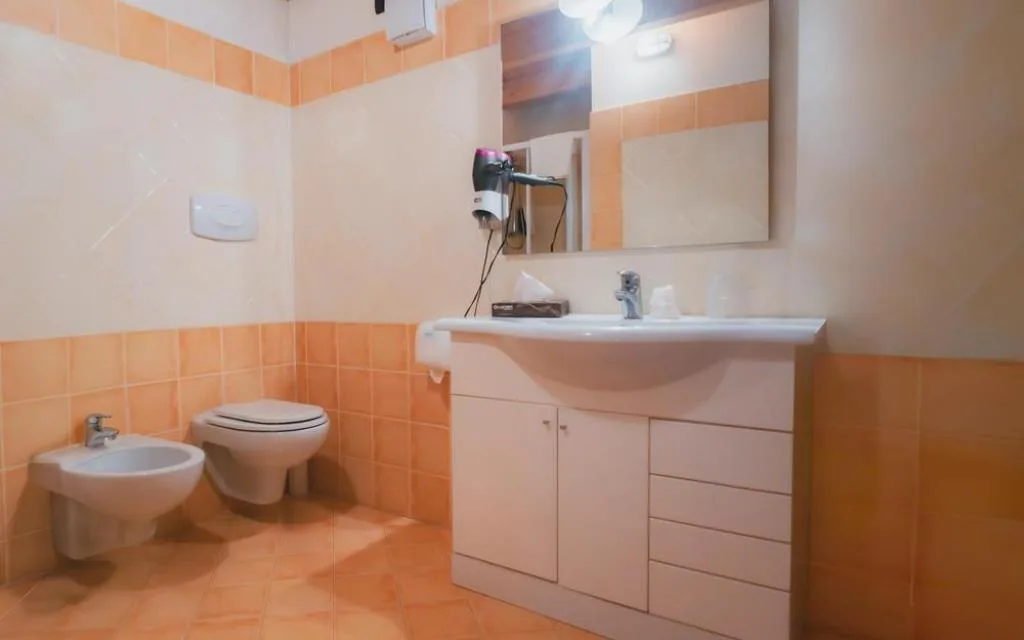 Bagno con lavabo, bidet, WC sospeso e piastrelle nei toni dell'arancio