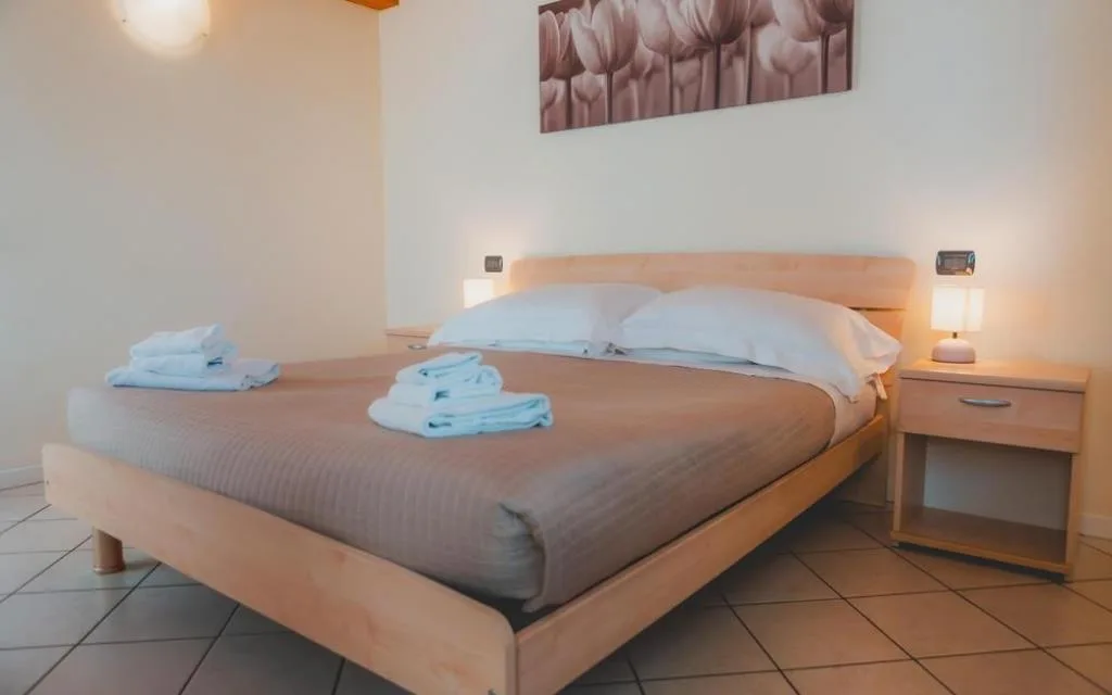 Camera da letto matrimoniale con testiera in legno e pavimento in cotto