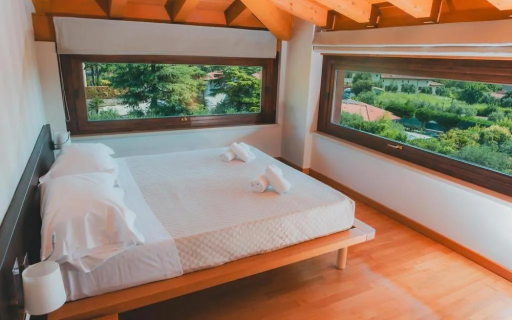 Camera con letto matrimoniale a soppalco e finestre panoramiche sul verde