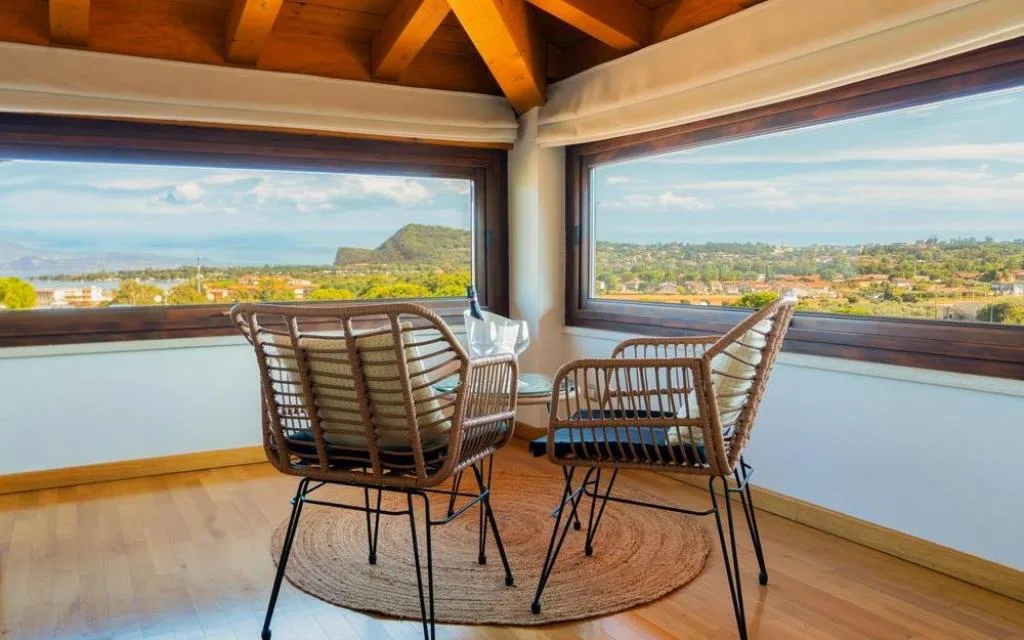 Angolo relax con poltrone in rattan e ampie finestre con vista sul lago di Garda
