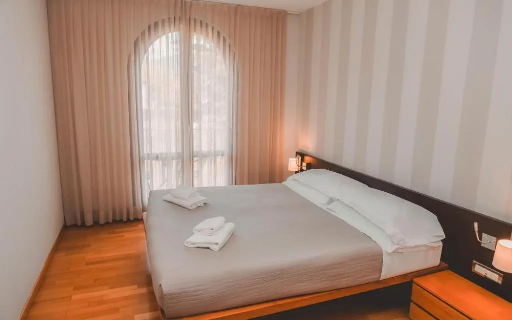 Camera da letto con pareti a righe e ampia finestra ad arco