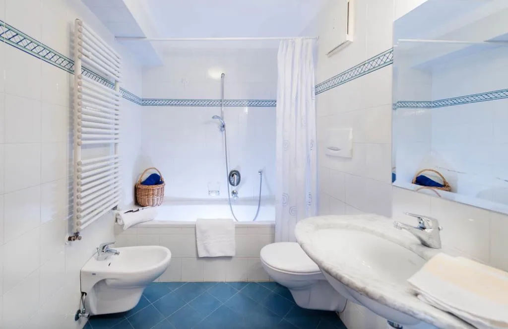 Bagno luminoso con vasca, bidet, WC e pavimento in piastrelle blu