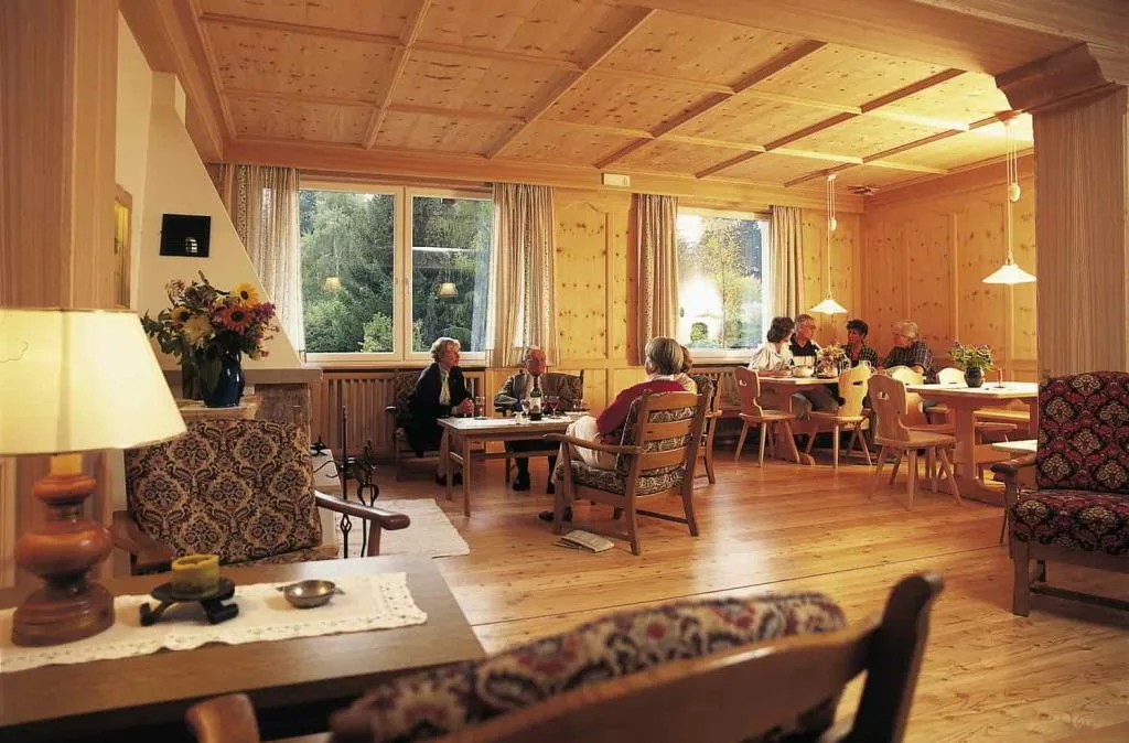 Sala comune rivestita in legno con ospiti seduti ai tavoli