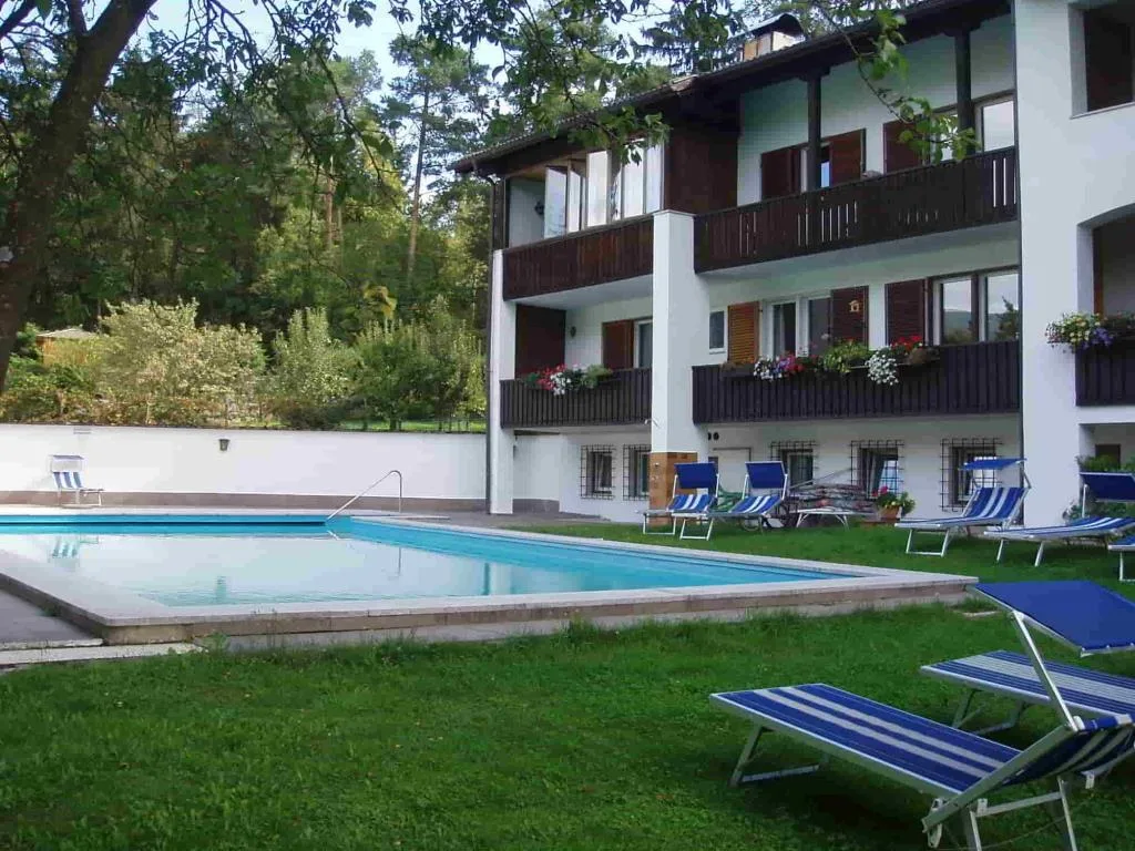 Piscina esterna con lettini a righe blu accanto all'edificio dell'hotel