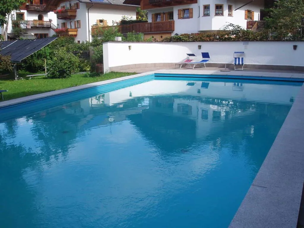 Piscina esterna con acqua azzurra e case alpine sullo sfondo