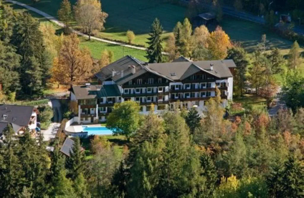 Veduta aerea dell'hotel con piscina immerso nel bosco autunnale