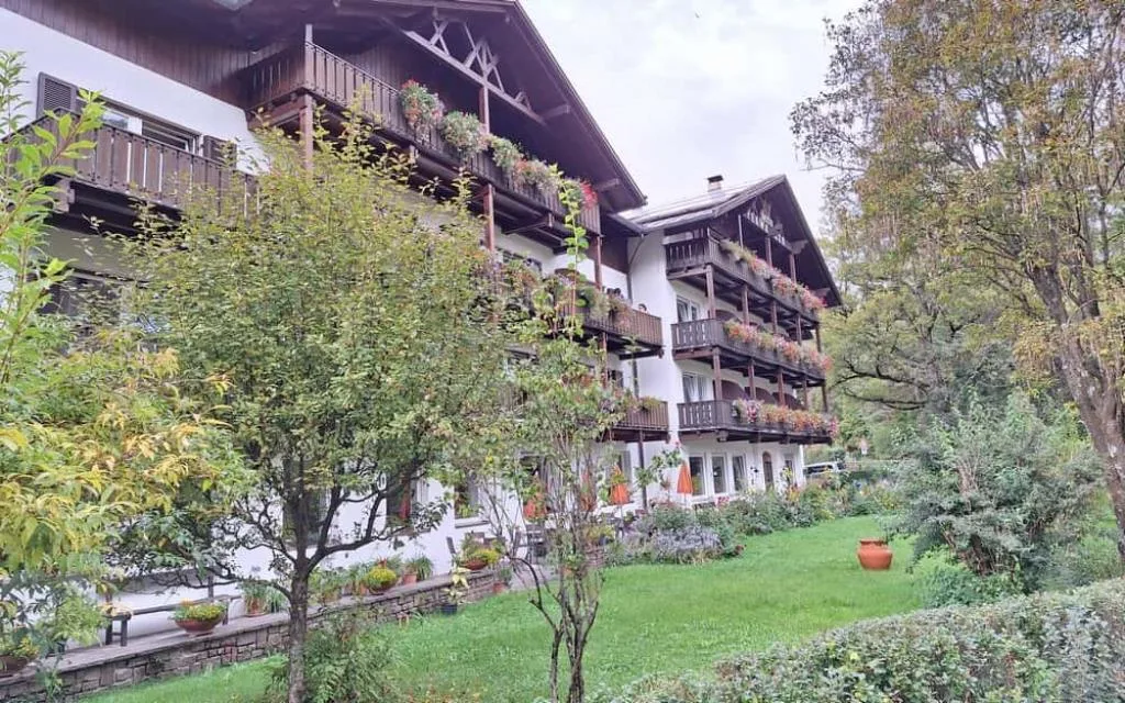 Facciata dell'hotel con balconi fioriti e giardino verde